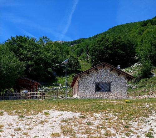 a small stone building in a field with a hill at Le Tre Dimore - Rifugio Aceroni in San Biagio Saracinesco