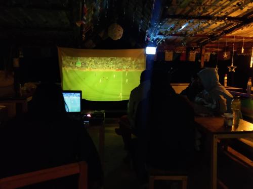 a group of people watching a soccer game on a screen at Ikigai Manali in Nagar