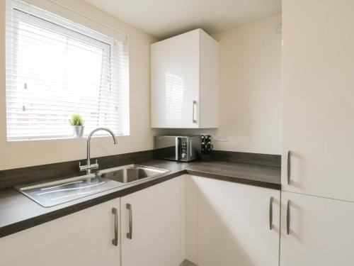 a kitchen with white cabinets and a sink and a window at The Green in Whitby