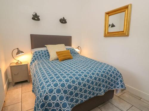 a bedroom with a bed with a blue comforter and a mirror at Willow Cottage in Aberystwyth