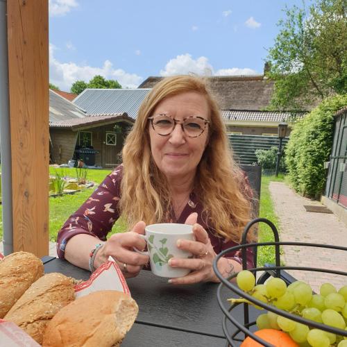 a woman sitting at a table with a cup of coffee at B&B Het Gelders Buitenleven in Overasselt