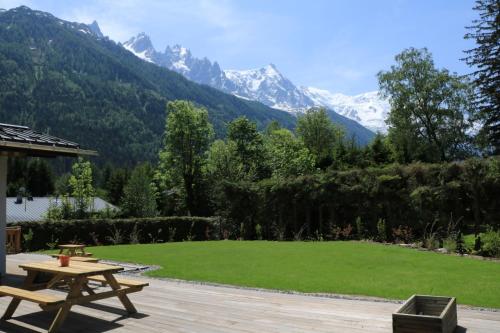 a picnic table and a lawn with mountains in the background at Chalet Pleine Vue & Spa in Chamonix-Mont-Blanc