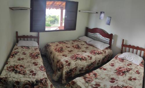 a bedroom with two beds and a window at Casa Beira Lago in Capitólio