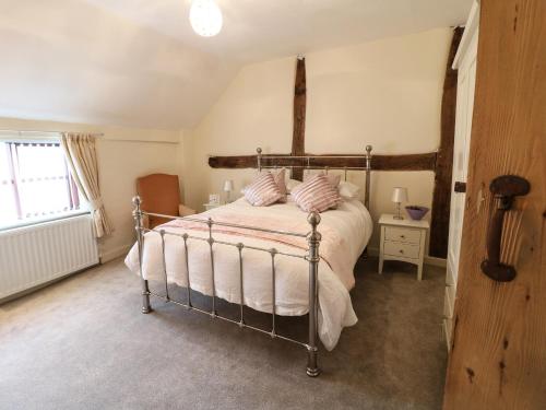 a bedroom with a bed with white sheets and a window at Hobson's Cottage 10 Main Street in Ilkeston