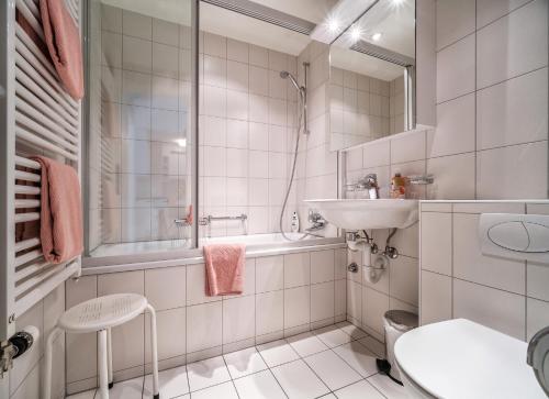 ein weißes Bad mit einem Waschbecken und einer Dusche in der Unterkunft Bristol 41 Ferienwohnung im Herzen von Arosa in Arosa