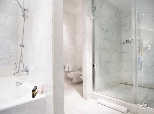 a white bathroom with a shower and a toilet at Hospes Palacio de los Patos in Granada