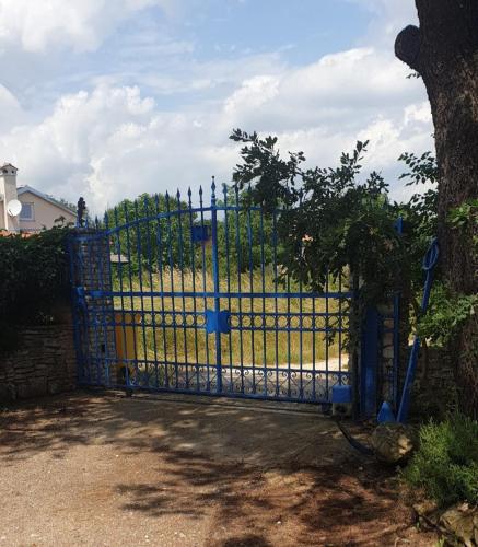 a blue metal gate with a field behind it at Apartments Nena 3* in Ližnjan