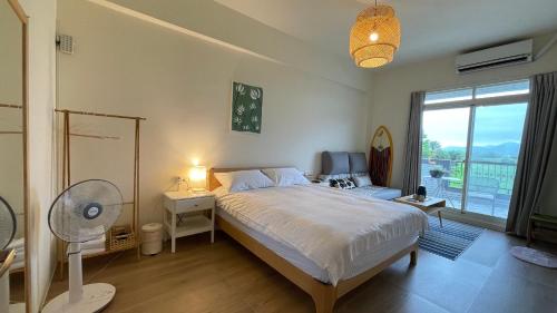 a bedroom with a bed with a fan and a window at 根本町無印風Villa包棟寵物友善 朋友聚會 烤肉廚房 兒童友善 in Yilan City
