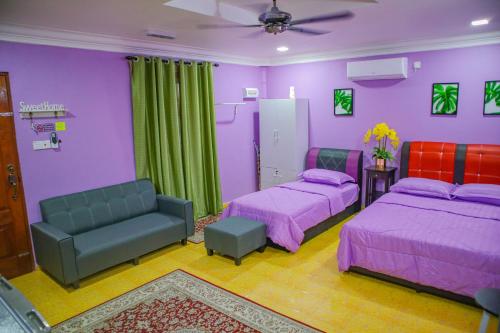 a purple room with two beds and a couch at GM Roomstay Kuala Besut in Kampong Gong Manok