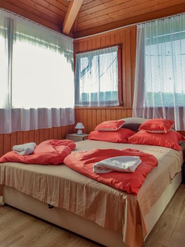 two beds in a room with windows and red sheets at Rózsapark Panoráma-apartman - maximum 4 fő részére in Demjén