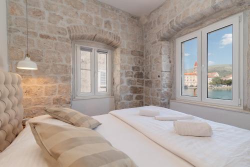 two beds in a room with two windows at Residence Providenca in Trogir