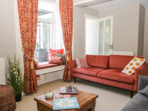 a living room with a red couch and a table at Yewbarrow Cottage in Grange Over Sands