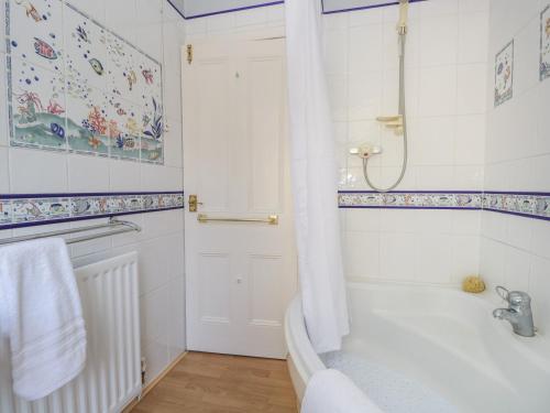 een witte badkamer met een bad en een douche bij Yewbarrow Cottage in Grange Over Sands