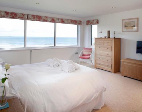 a bedroom with a large white bed with a view of the ocean at The White House in Polzeath