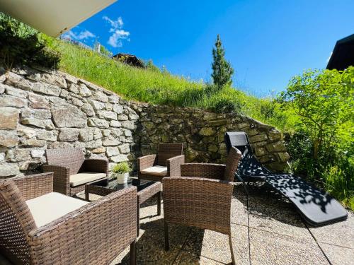 a patio with wicker chairs and a stone wall at Appart Kofler in Gerlos