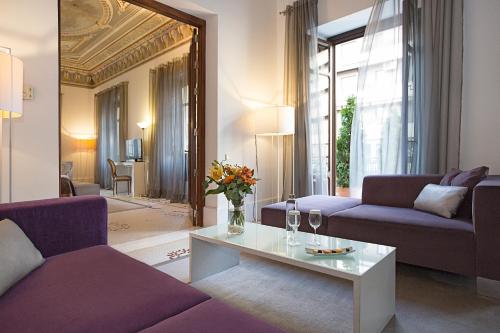 a living room with purple couches and a table at Hospes Palacio de los Patos in Granada