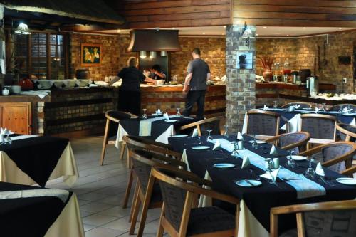 a restaurant with tables and chairs with people in the kitchen at Legend Safaris 257A - in Kruger Park Lodge in Hazyview