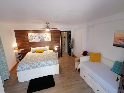 Un dormitorio con una cama blanca y un sofá. en Rancho Jardines de Marchenilla, en Alcalá de Guadaira