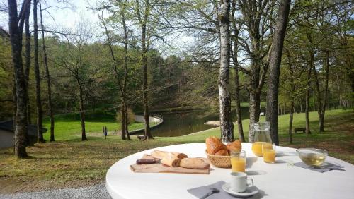 einen Tisch mit einem Teller Brot und Gläsern Orangensaft in der Unterkunft Résidence de Tourisme LE VENDAHAUT in Lapleau