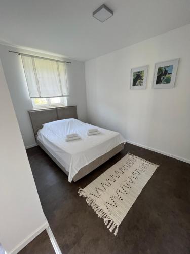 a white bedroom with a bed and a window at Mozgan Apartments in Piran