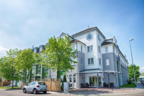 un edificio bianco con un'auto parcheggiata di fronte di ACHAT Hotel Leipzig Messe a Lipsia