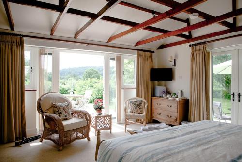 a bedroom with a bed and two chairs and a window at The Old Hop Kiln Barn in Petersfield
