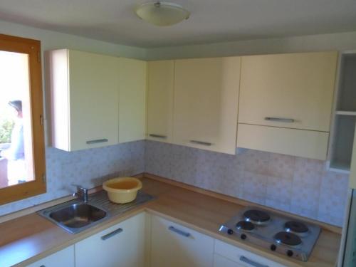 Una cocina con gabinetes blancos y un fregadero y una ventana. en VARDIOLA/PORTO VECCHIO, en Pinarellu