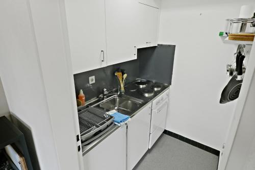 a white kitchen with a sink and a stove at Nouveau studio avec vue imprenable sur la vallée in Leukerbad