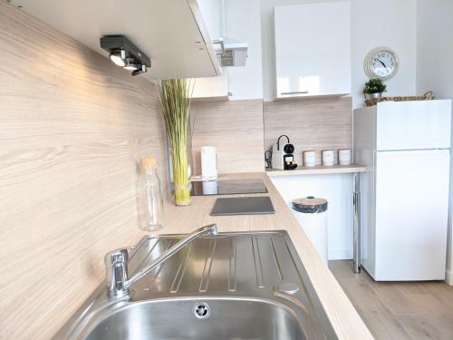 una cucina con lavandino e frigorifero bianco di Cosy Iris - 3 Ch- Lumineux avec parking gratuit a Pau