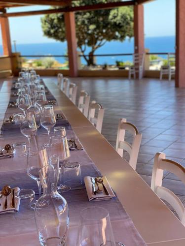 a long table with wine glasses and white chairs at Hotel Trinità dei Corsari in Torre Dei Corsari