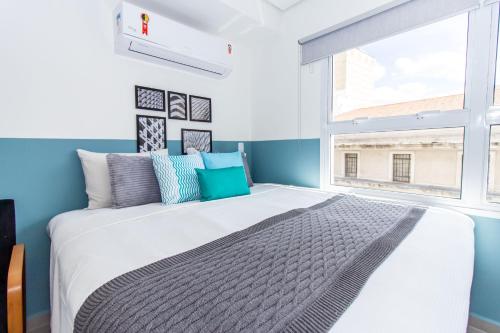 1 dormitorio con 1 cama grande, paredes azules y ventana en 360 Suítes San Fran - Apartamentos mobiliados, en São Paulo