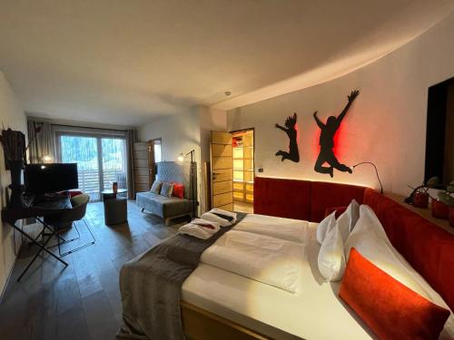 a bedroom with a bed with two jumping people on the wall at SPA & Relax Hotel Erika in Tirolo
