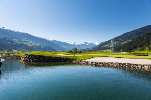 a golf course with a lake and mountains in the background at Central Hotel & Apart mit Landhaus Central in Fügen