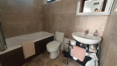 a bathroom with a toilet and a sink and a bath tub at Mayday Cottage in Pócsmegyer