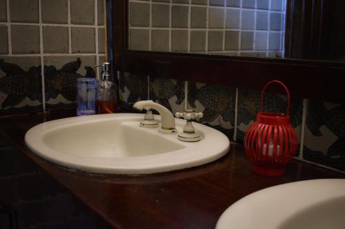 a bathroom sink with a red vase on a counter at Numa Boa HOSTEL Búzios in Búzios