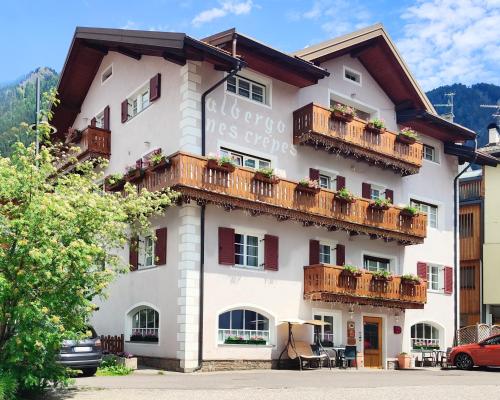 a large white building with balconies on it at Hotel Garnì Nès Crépes in Pozza di Fassa