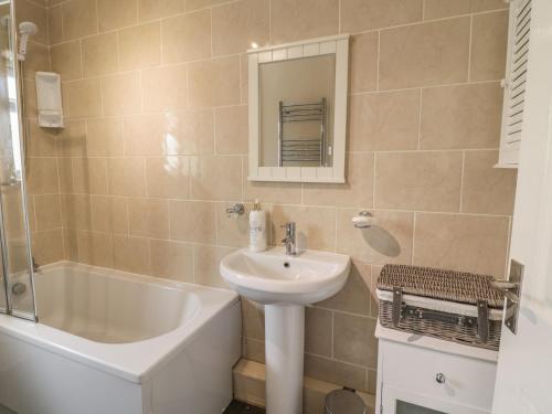 a bathroom with a sink and a bath tub next to a sink at The Old Smithy Cottage in Blaenau-Ffestiniog