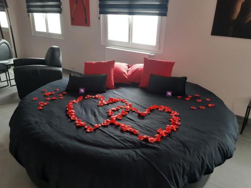 Una cama con un corazón hecho de rosas rojas en Ds Plaisir Love Room avec sauna, jacuzzi à Nancy en Nancy