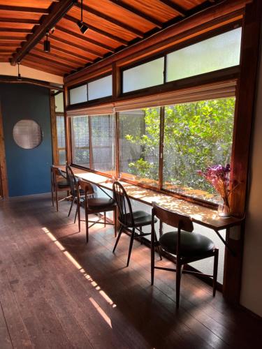 北九州市にある門司港ゲストハウスPORTO（ポルト）の大きな窓のある客室で、長いテーブルと椅子が備わります。
