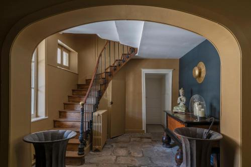un couloir avec escalier en colimaçon et tabourets dans l'établissement La Maison Pavie, à Dinan