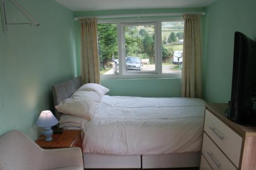 a bedroom with a bed and a window at Coynant Farm Guesthouse - Farm Park Stay in Swansea