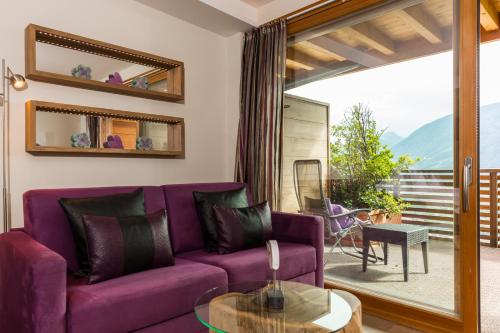 a living room with a purple couch and a glass table at SPA & Relax Hotel Erika in Tirolo