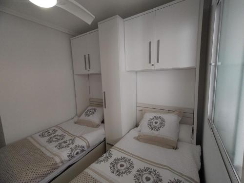 twee bedden in een kleine kamer met witte kasten bij Lovely apartment with pool view in Orihuela