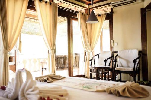 a room with two beds and a large window at Amed Cafe & Hotel Kebun Wayan in Amed