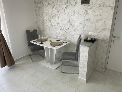 einen weißen Tisch mit 2 Stühlen und einen Tisch mit Weingläsern in der Unterkunft Luxory Apartaments 2 in Costinești