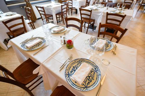 a dining room with white tables with plates and napkins at Albergo Locanda Primavera in Rodengo Saiano