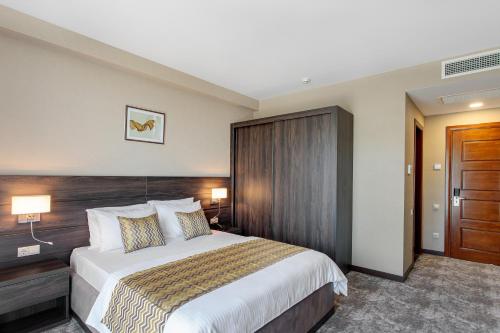 a bedroom with a large bed and a wooden door at Vinum Hotel in Tbilisi City