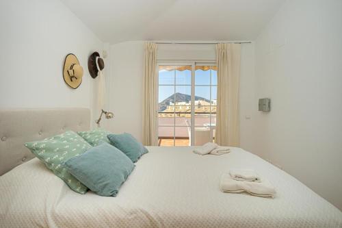 a white bed with blue pillows and a window at Apartament Altea Spaniahome in Altea