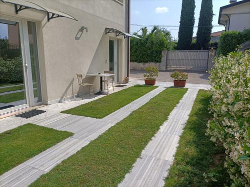 a garden with grass and a table in front of a house at Garda Guest House in Colà di Lazise