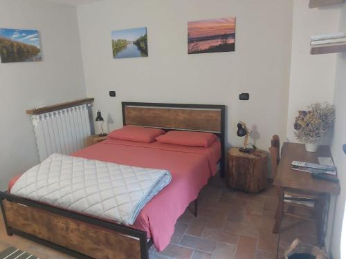 Cette chambre comprend un lit avec des oreillers rouges et un bureau. dans l'établissement B&B La Casa sul Fiume, à San Martino dallʼ Argine